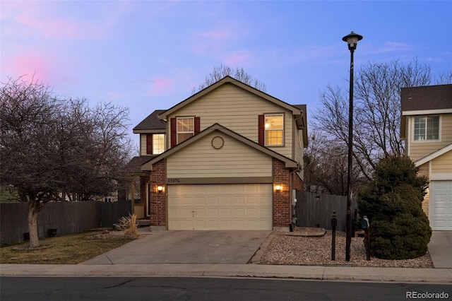 view of front of property with a garage, concrete driveway, brick siding, and fence