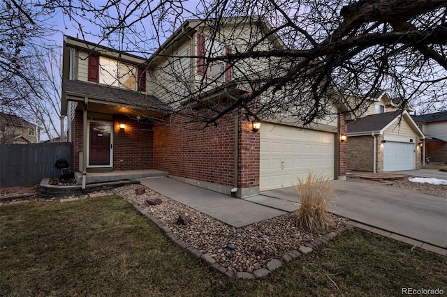 traditional home featuring driveway, a garage, brick siding, fence, and a front yard