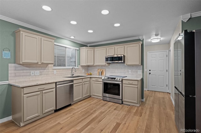 kitchen featuring appliances with stainless steel finishes, light wood-type flooring, crown molding, and a sink