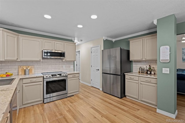 kitchen with baseboards, appliances with stainless steel finishes, crown molding, light wood-style floors, and backsplash