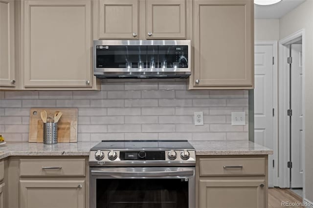 kitchen featuring appliances with stainless steel finishes, light stone counters, and tasteful backsplash