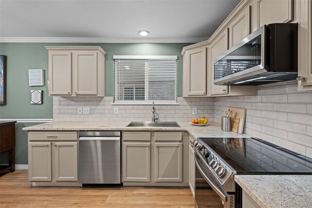 kitchen featuring stainless steel appliances, a sink, light wood-style flooring, and ornamental molding