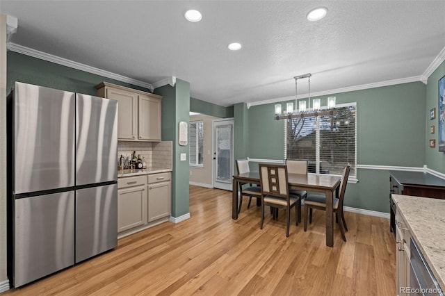 kitchen featuring stainless steel appliances, decorative backsplash, light wood-style floors, ornamental molding, and a chandelier