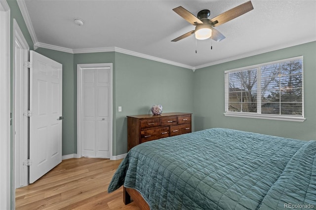 bedroom with ceiling fan, light wood-style flooring, baseboards, a closet, and crown molding