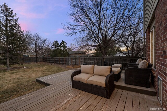 deck at dusk featuring an outdoor hangout area, a lawn, and a fenced backyard