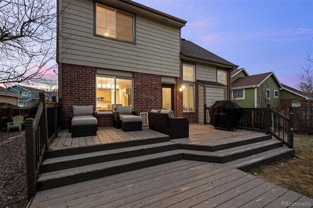 deck at dusk with a grill and fence