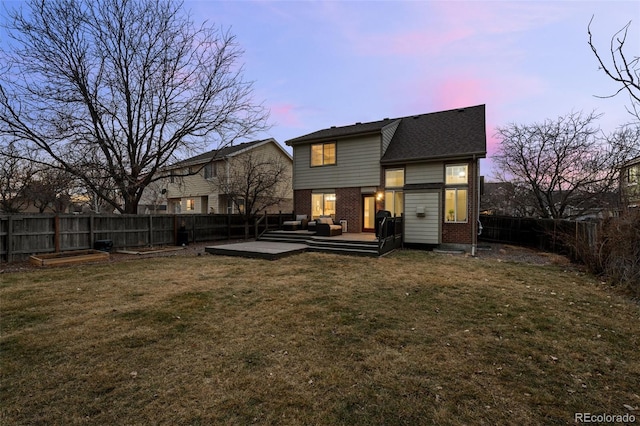 rear view of property featuring a vegetable garden, brick siding, a yard, and a fenced backyard