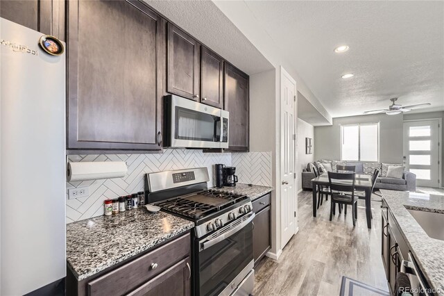 623 S Pitkin Ct, Aurora, CO 80017 - kitchen featuring dark brown cabinets, backsplash, open floor plan, and appliances with stainless steel finishes