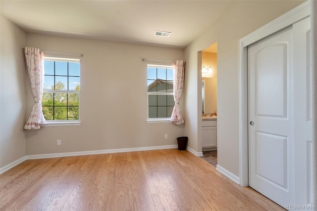 unfurnished bedroom with light wood-type flooring, connected bathroom, and a closet