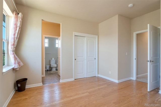 unfurnished bedroom with light wood-type flooring, connected bathroom, and a closet