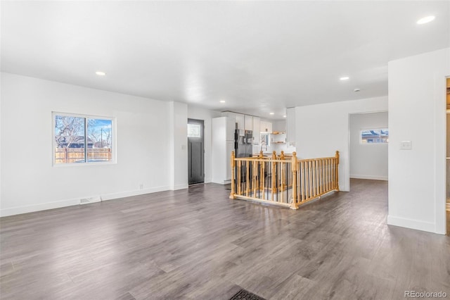 unfurnished living room with recessed lighting, dark wood-type flooring, baseboards, and a sink