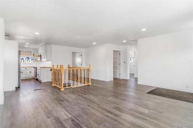 unfurnished living room featuring recessed lighting, wood finished floors, and baseboards