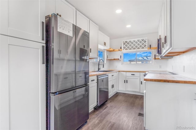 kitchen featuring butcher block countertops, white cabinets, stainless steel appliances, and a sink