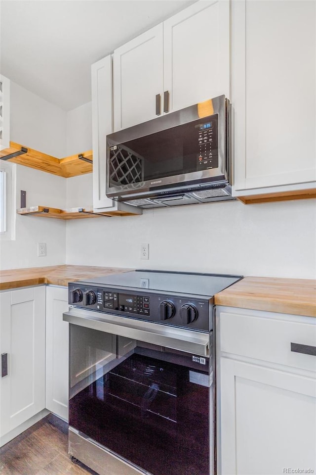 kitchen with wood counters, white cabinets, wood finished floors, and stainless steel appliances