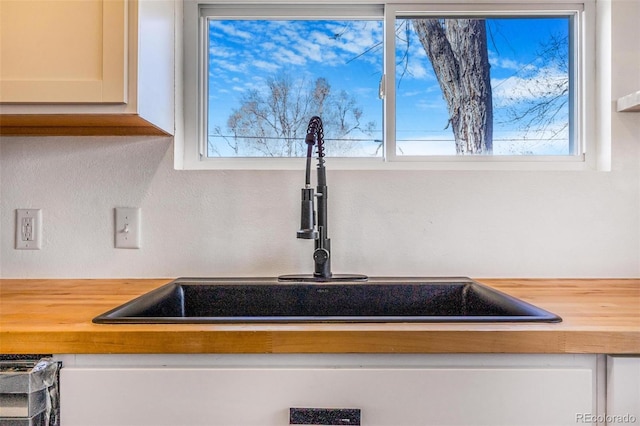 room details featuring wood counters, white cabinetry, and a sink