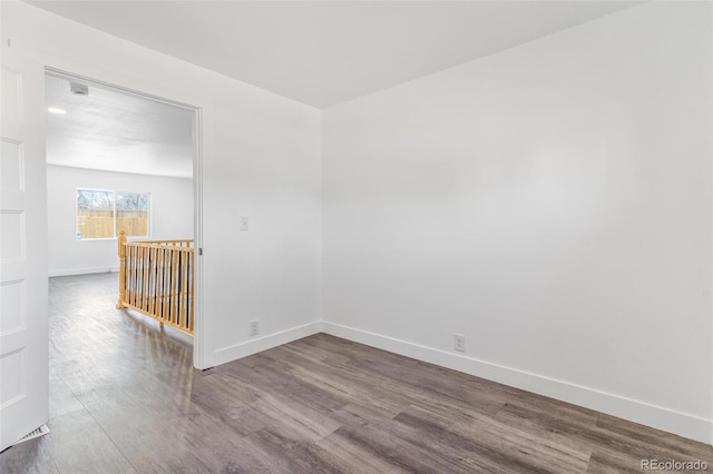 spare room featuring baseboards and wood finished floors