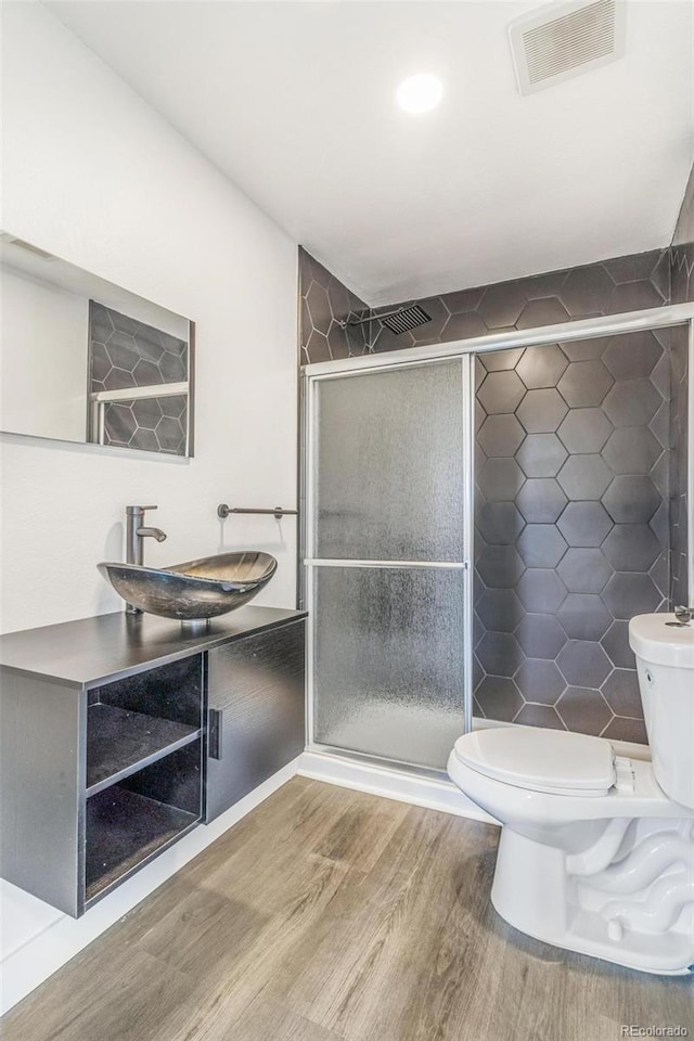 full bathroom featuring toilet, wood finished floors, visible vents, and a sink