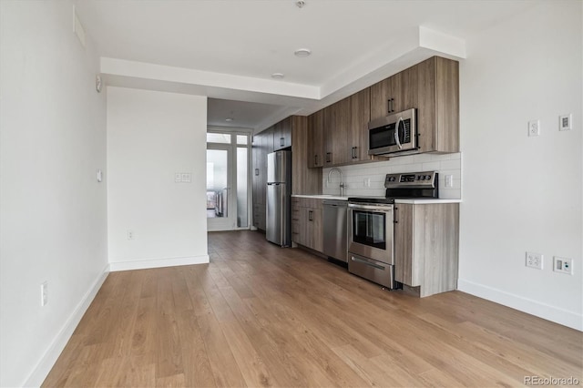 kitchen featuring decorative backsplash, sink, stainless steel appliances, and light wood-type flooring