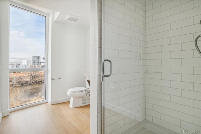 bathroom with wood-type flooring, an enclosed shower, and toilet