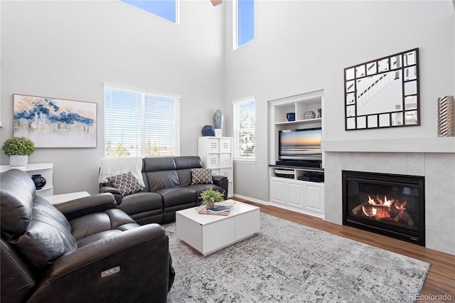 living room with a fireplace, built in shelves, hardwood / wood-style flooring, and a high ceiling