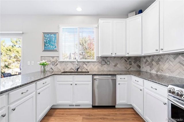 kitchen featuring white cabinetry, sink, dark stone counters, and appliances with stainless steel finishes