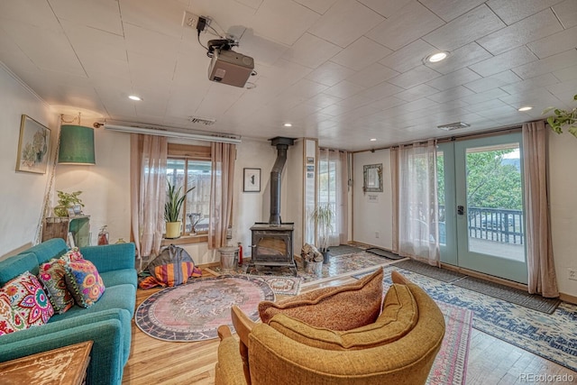 living room featuring hardwood / wood-style floors, a wood stove, french doors, and ornamental molding