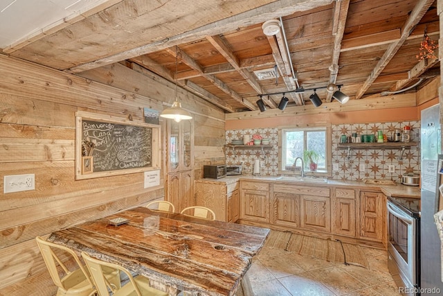 kitchen with sink, light brown cabinets, stainless steel electric range oven, hanging light fixtures, and wood walls