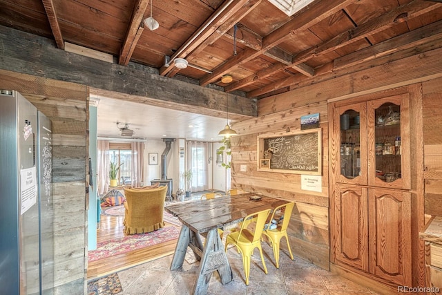 dining space with beam ceiling, wooden walls, and wood ceiling