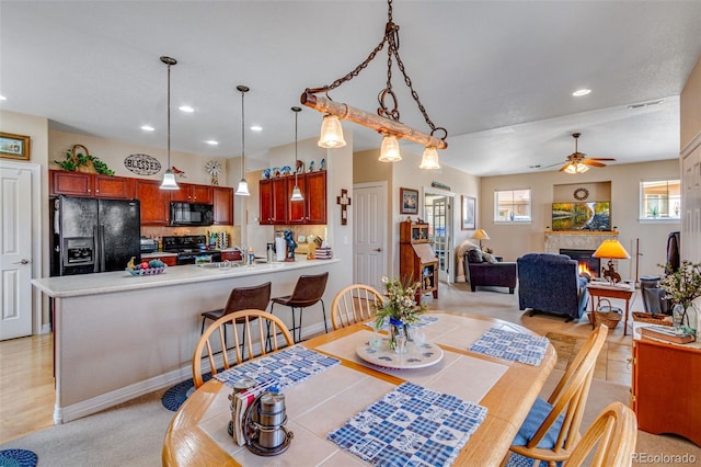 dining area featuring a warm lit fireplace, a ceiling fan, and recessed lighting