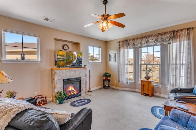 carpeted living area featuring a ceiling fan, a tile fireplace, visible vents, and baseboards