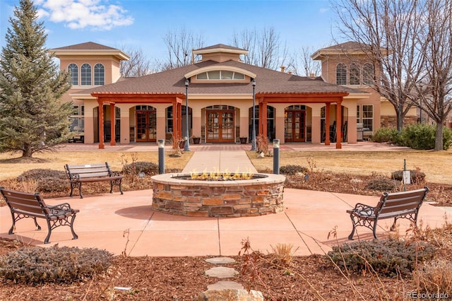 exterior space featuring french doors, a fire pit, and stucco siding