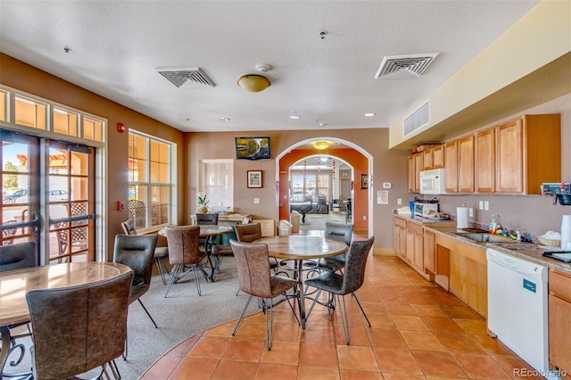 kitchen featuring arched walkways, white appliances, visible vents, and a sink