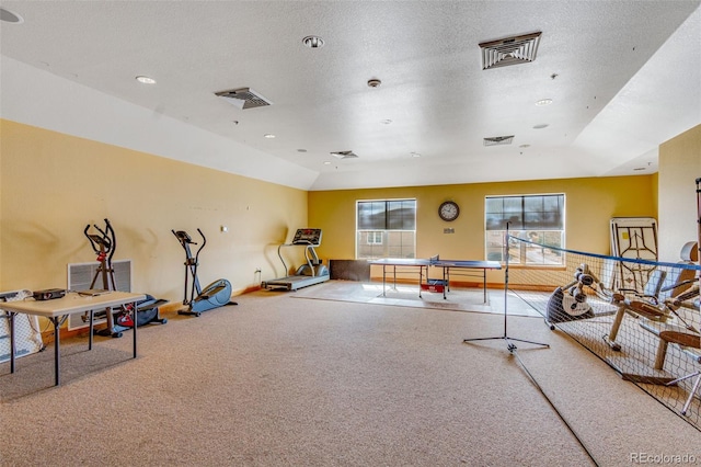 exercise room featuring carpet floors, visible vents, vaulted ceiling, and a textured ceiling