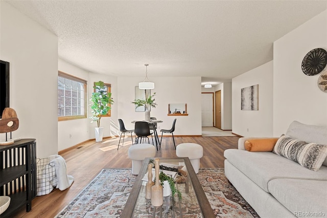 living room with light wood-style floors, baseboards, and a textured ceiling