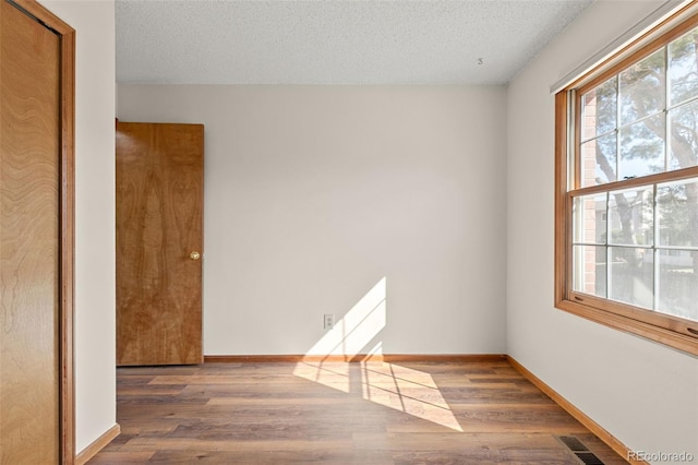 unfurnished room with visible vents, a textured ceiling, and wood finished floors