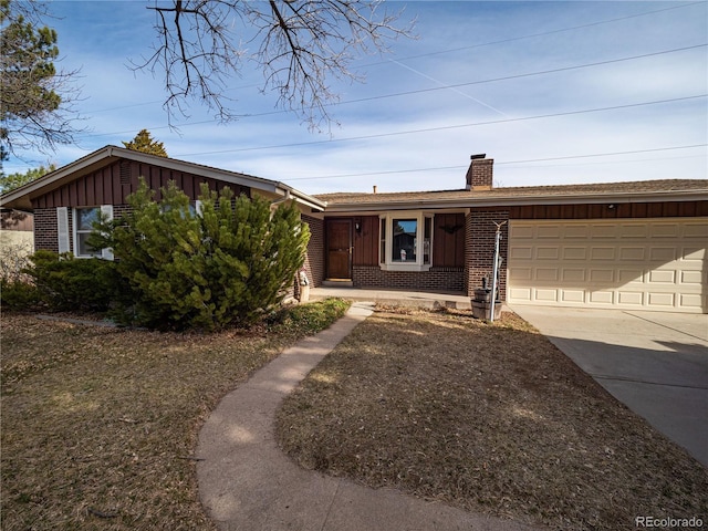 view of front of property featuring driveway, board and batten siding, an attached garage, brick siding, and a chimney