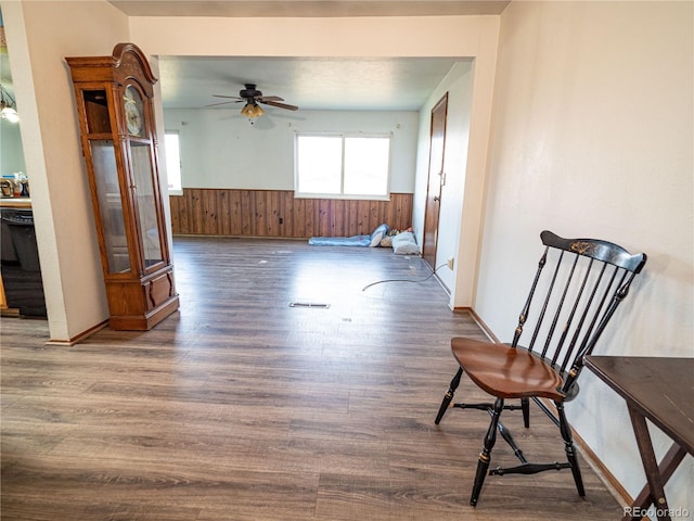 empty room featuring ceiling fan, wooden walls, wood finished floors, and wainscoting