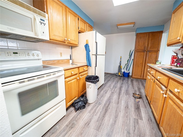 kitchen featuring decorative backsplash, white appliances, light countertops, and light wood-style floors