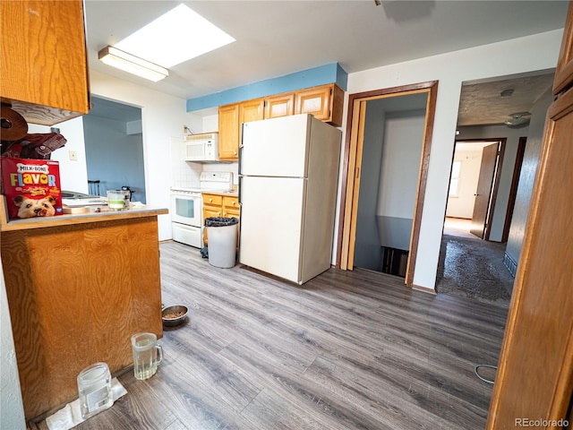 kitchen with backsplash, light countertops, light wood-type flooring, a skylight, and white appliances