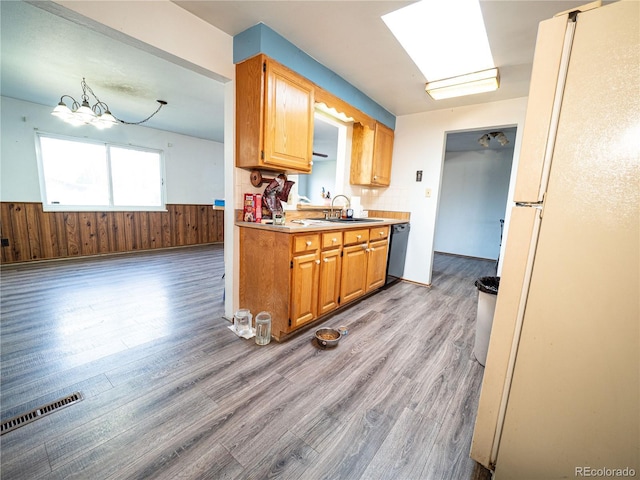 kitchen with visible vents, a wainscoted wall, dishwasher, freestanding refrigerator, and a sink