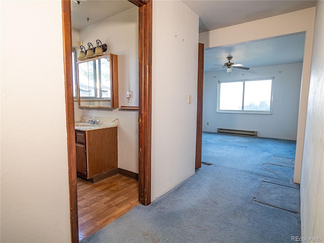 corridor with a sink, carpet, and a baseboard radiator