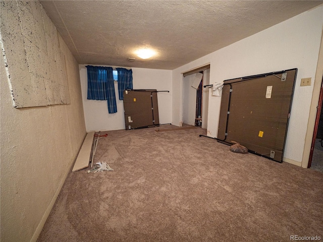 interior space featuring a textured ceiling, carpet flooring, and a textured wall