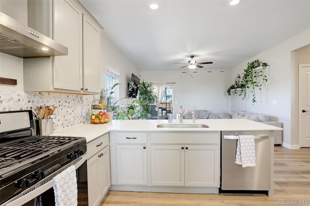 kitchen with stainless steel appliances, a peninsula, a sink, exhaust hood, and open floor plan