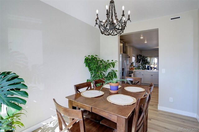 dining room with light wood finished floors, baseboards, and visible vents