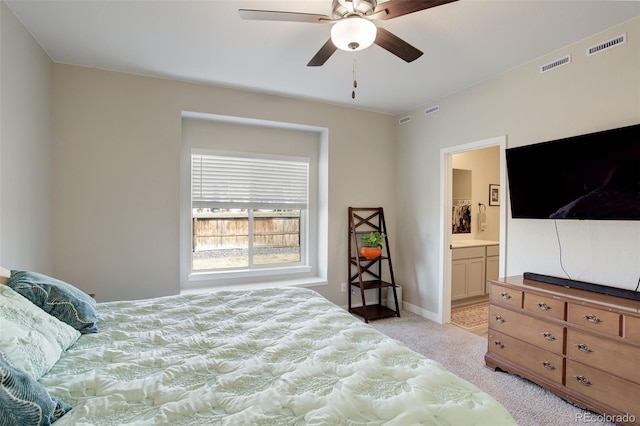 bedroom with light carpet, visible vents, and ensuite bathroom