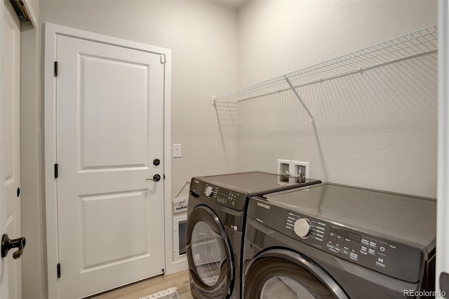 laundry area with laundry area, independent washer and dryer, and light wood-style flooring