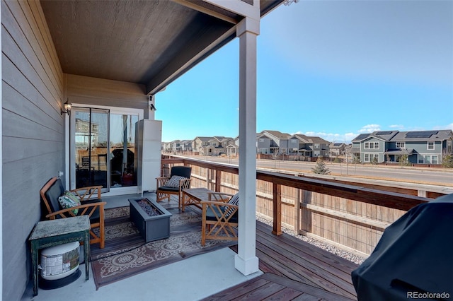 wooden deck with a residential view, a grill, and an outdoor fire pit