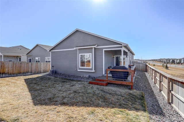 rear view of house with a fenced backyard, a deck, and a lawn