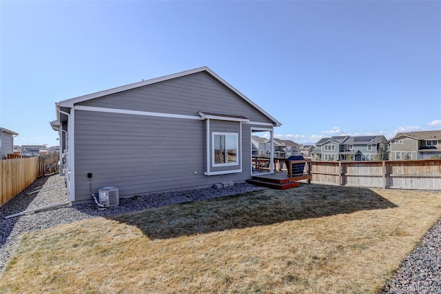 rear view of house with a wooden deck, central AC unit, a fenced backyard, a residential view, and a yard