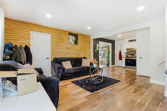 living room with wood-type flooring, a textured ceiling, and wooden walls